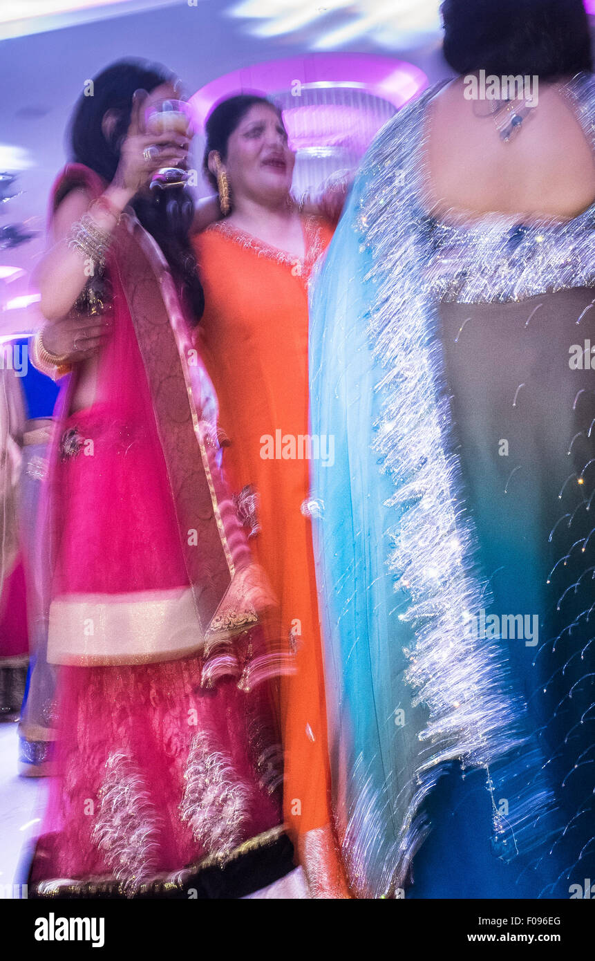Le donne indiane in sari colorati danzare al ricevimento di nozze Foto Stock