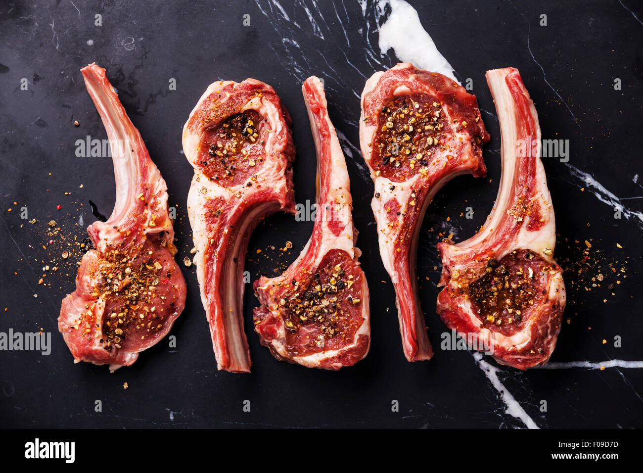 Crudo fresco di carne di montone costolette di agnello su nero Sfondo marmo Foto Stock