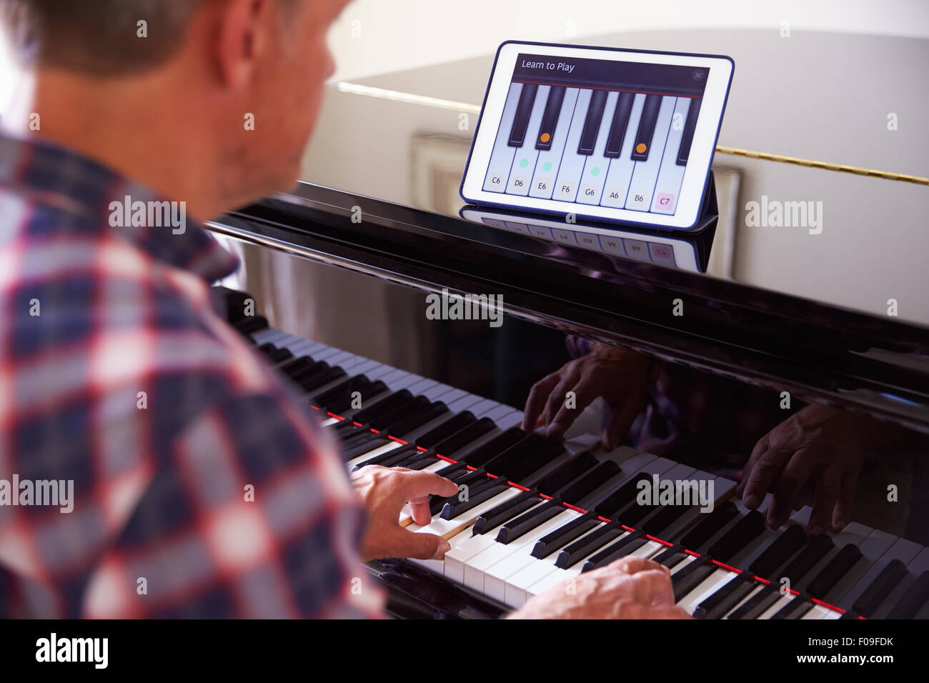 Uomo di imparare a suonare il piano utilizzando tavoletta digitale applicazione Foto Stock