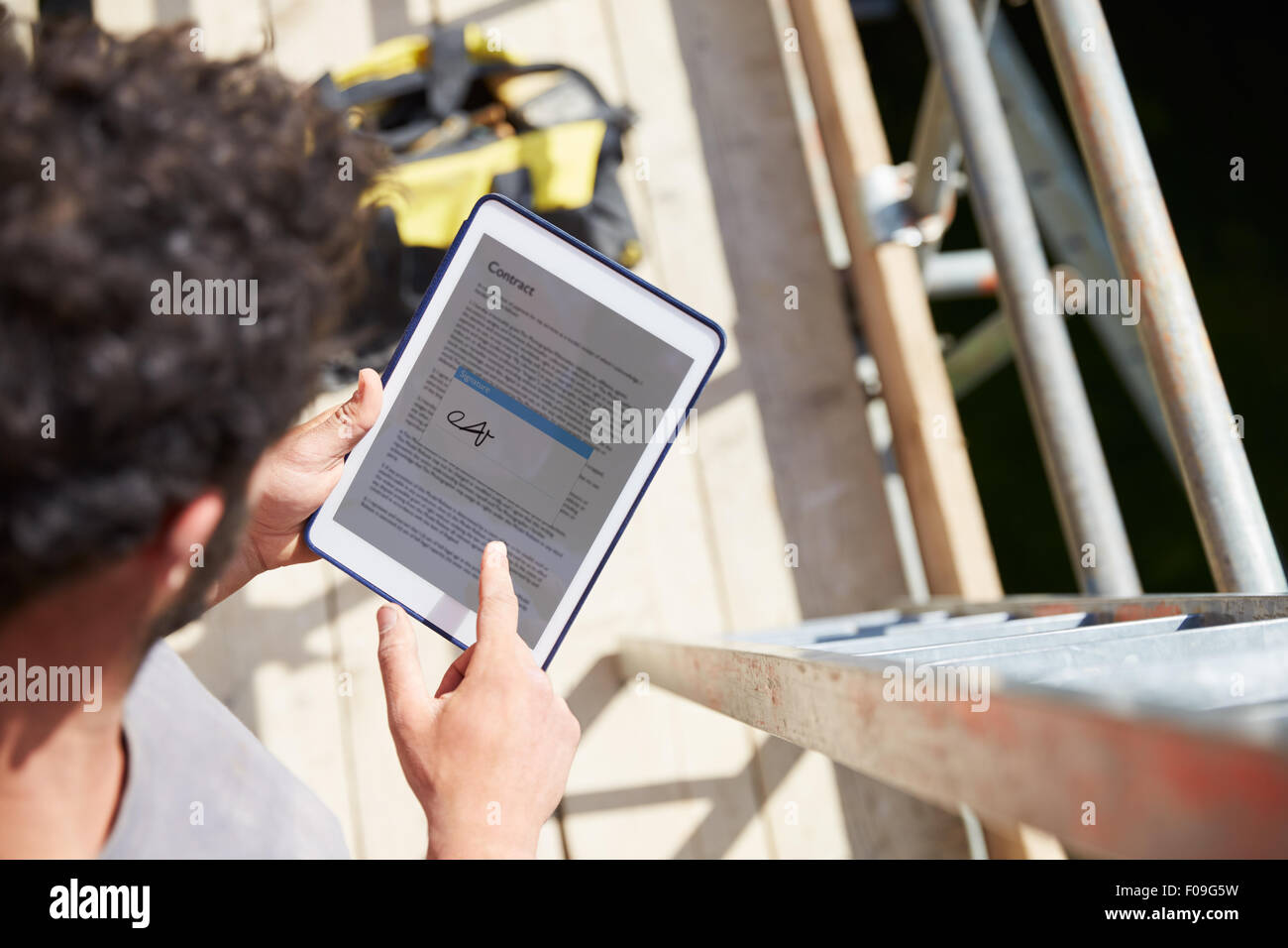 Operaio edile firma contratto sulla tavoletta digitale Foto Stock