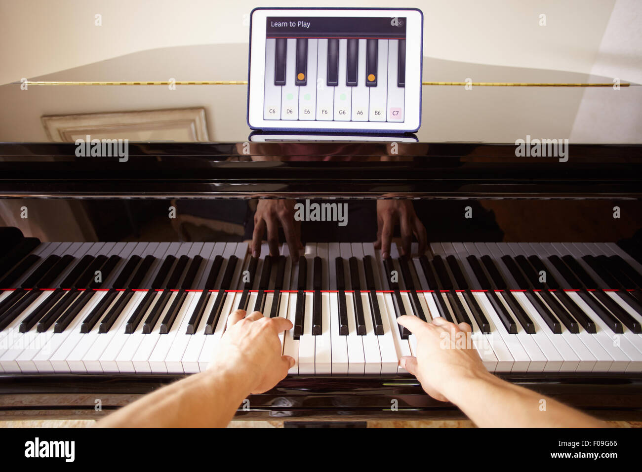 Uomo di imparare a suonare il piano utilizzando tavoletta digitale applicazione Foto Stock