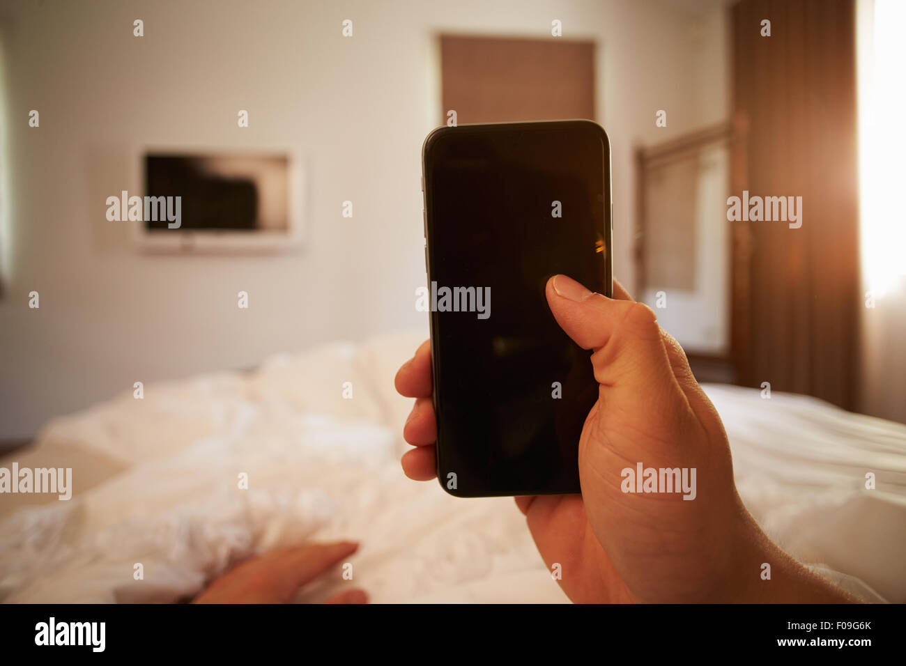 Punto di vista immagine della persona nel letto guardando al telefono cellulare Foto Stock