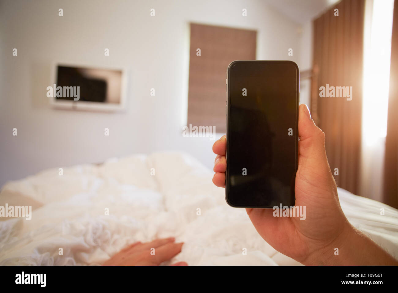 Punto di vista immagine della persona nel letto guardando al telefono cellulare Foto Stock