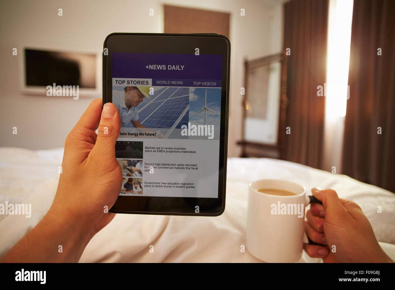 Uomo nel letto guardando il sito di notizie sulla tavoletta digitale Foto Stock