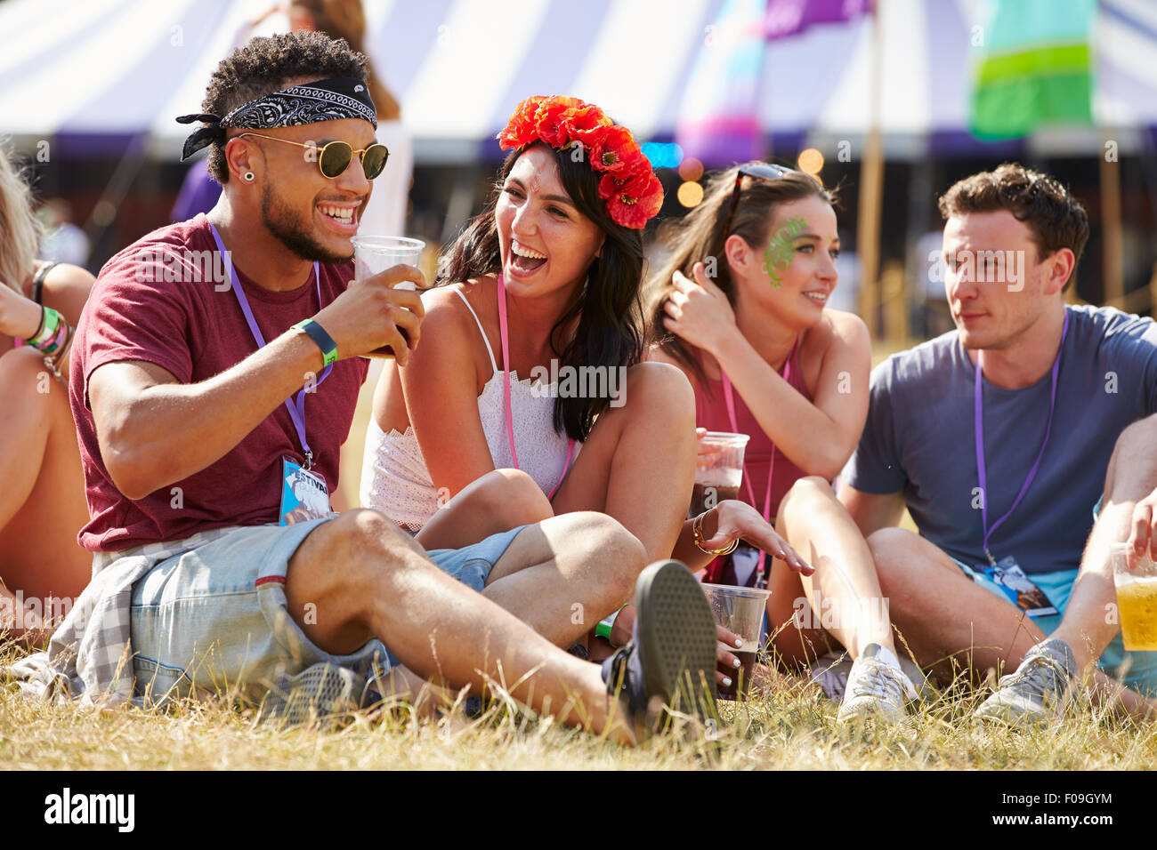 Amici seduti sul prato a parlare al festival di musica Foto Stock