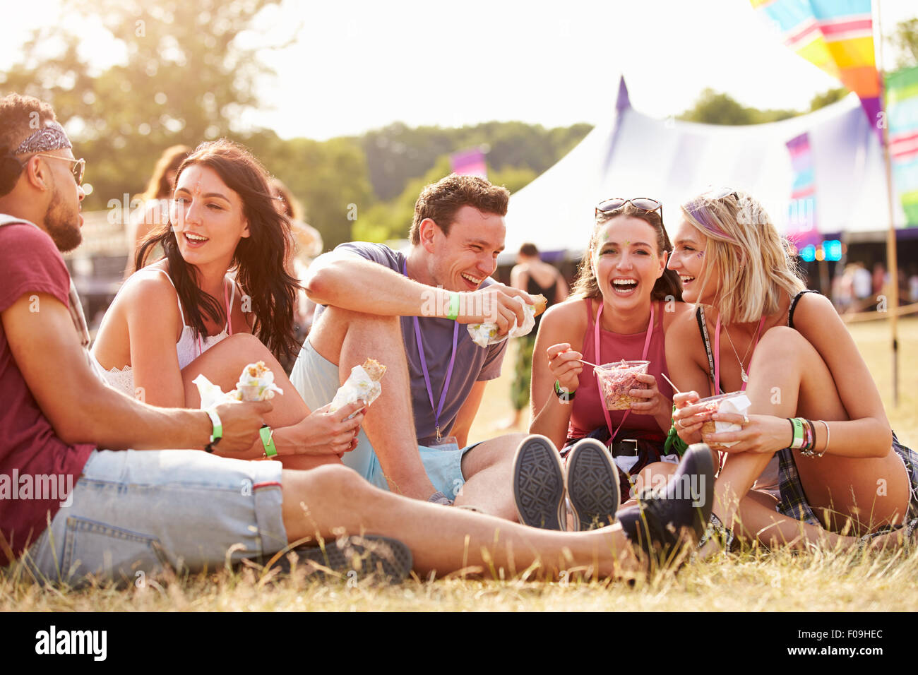 Amici seduti sul prato di mangiare a un festival di musica Foto Stock