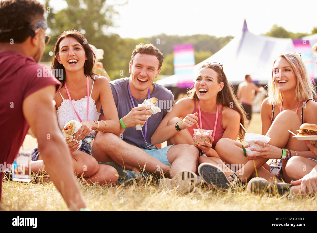 Amici seduti su erba e mangiare presso il festival di musica Foto Stock