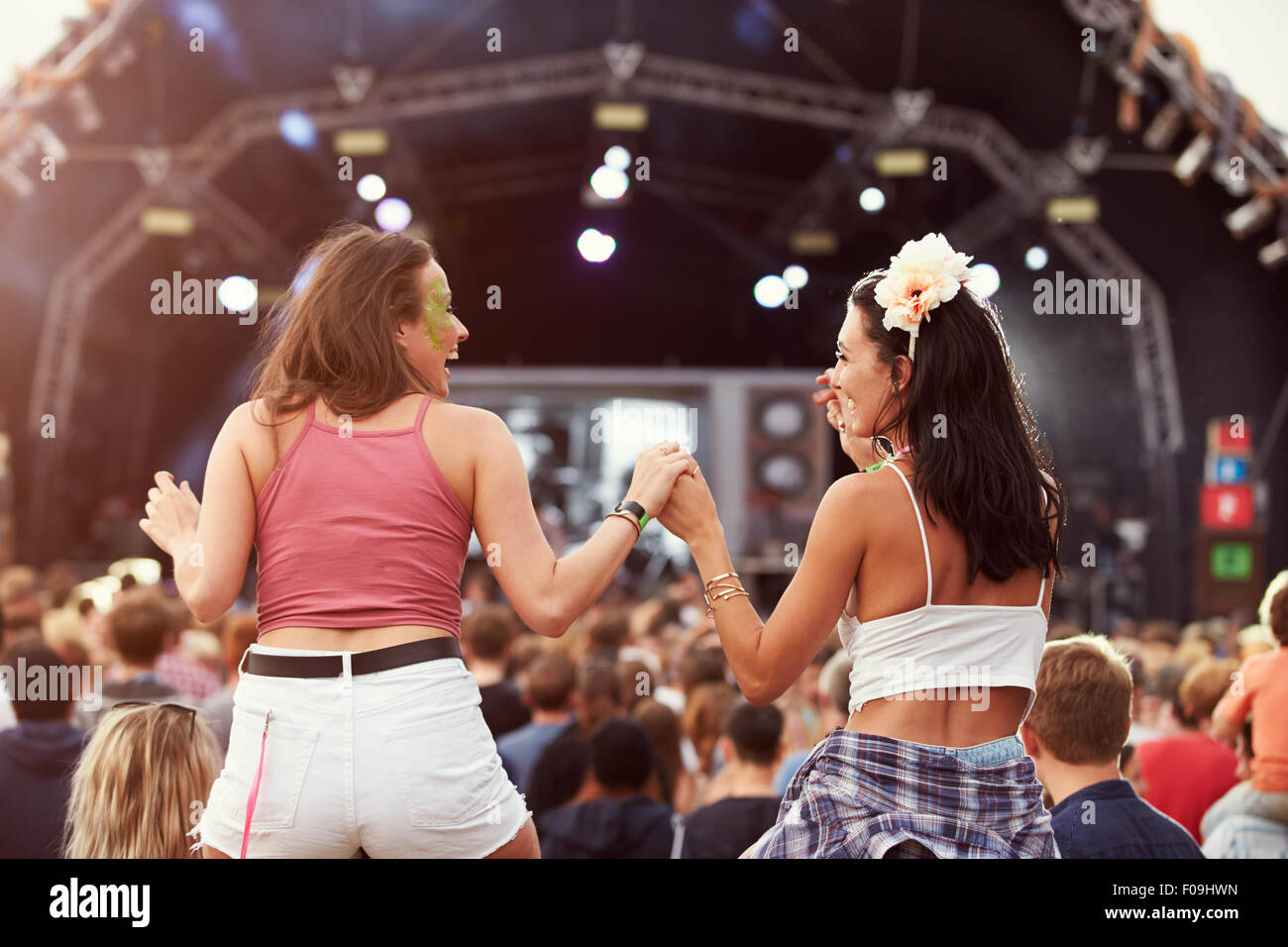 Due ragazze su spalle in mezzo alla folla a un festival di musica Foto Stock