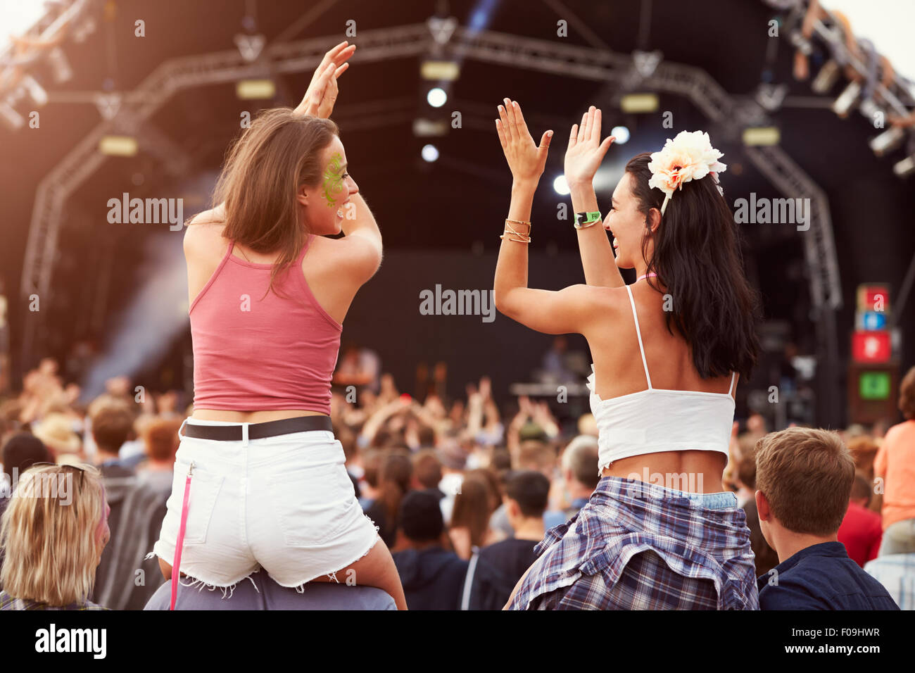 Due ragazze su spalle in mezzo alla folla a un festival di musica Foto Stock