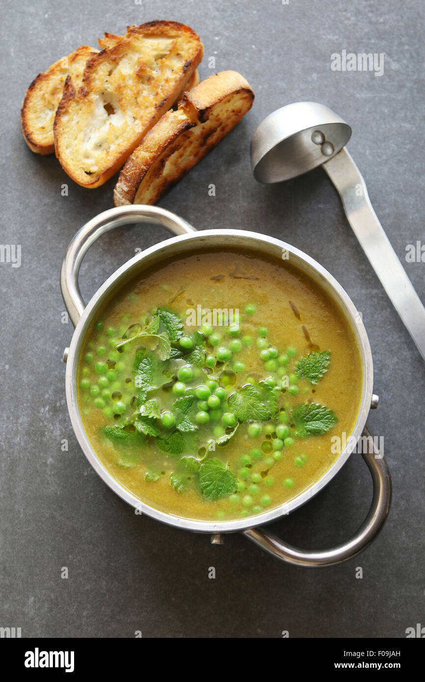 Verde zuppa di piselli in una teglia di alluminio guarnito con menta fresca Foto Stock