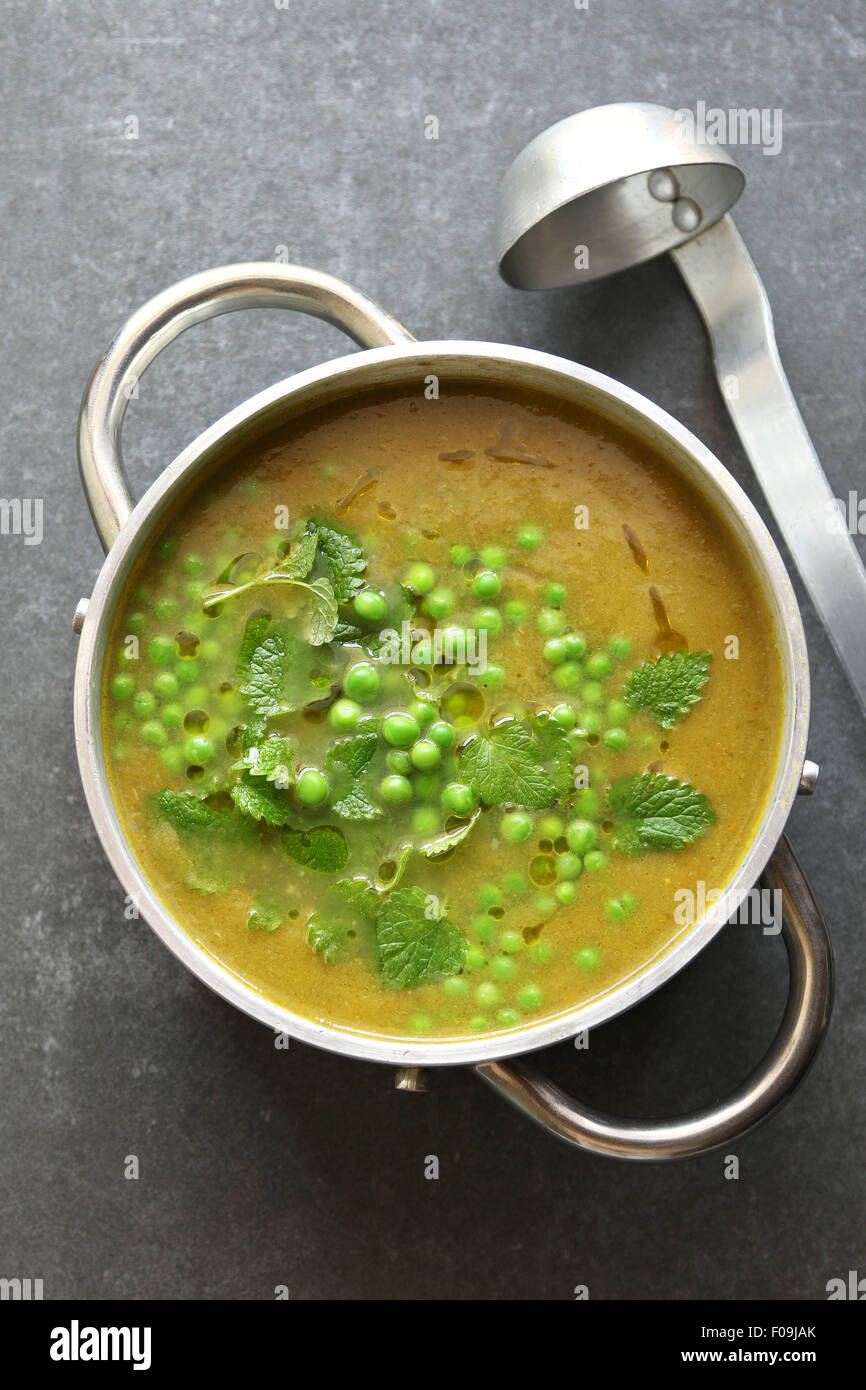 Verde zuppa di piselli in una teglia di alluminio guarnito con menta fresca Foto Stock