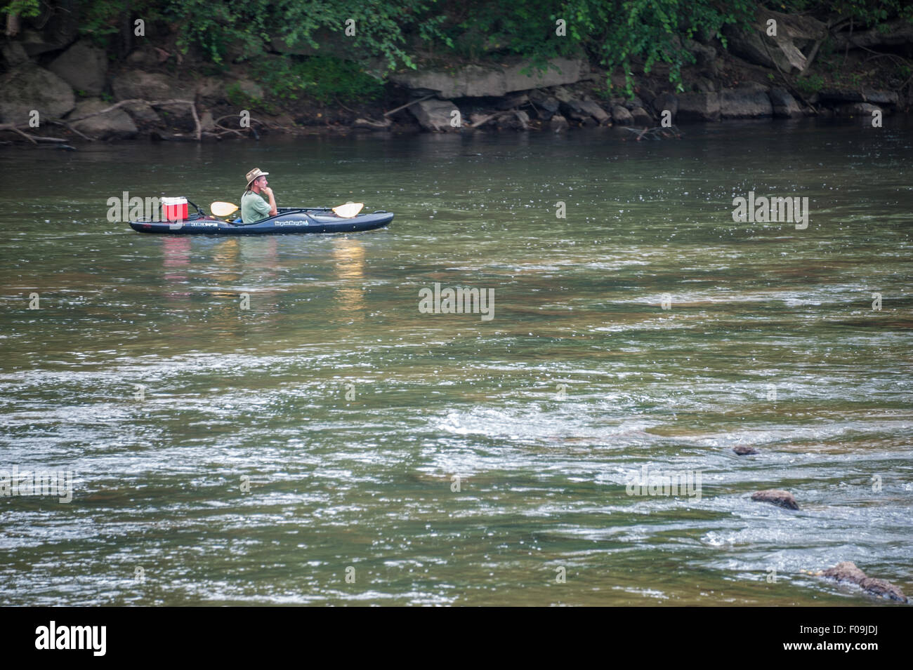 Un lone kayaker rilassa come egli derive pacificamente lungo il francese ampio fiume in Asheville, North Carolina, Stati Uniti d'America. Foto Stock