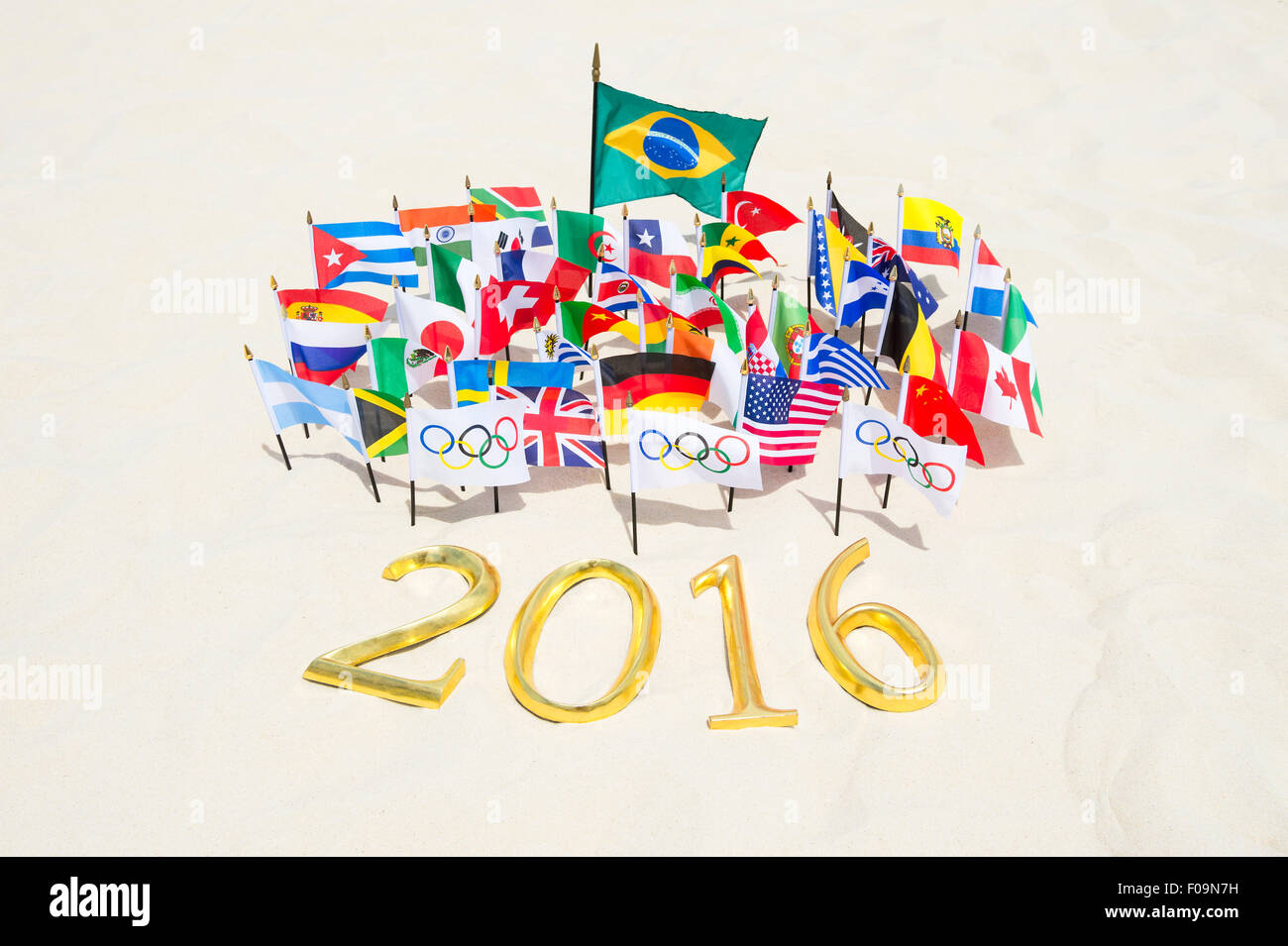 RIO DE JANEIRO, Brasile - 20 Marzo 2015: Golden 2016 segno si siede sulla sabbia con internazionale e bandiere olimpica. Foto Stock