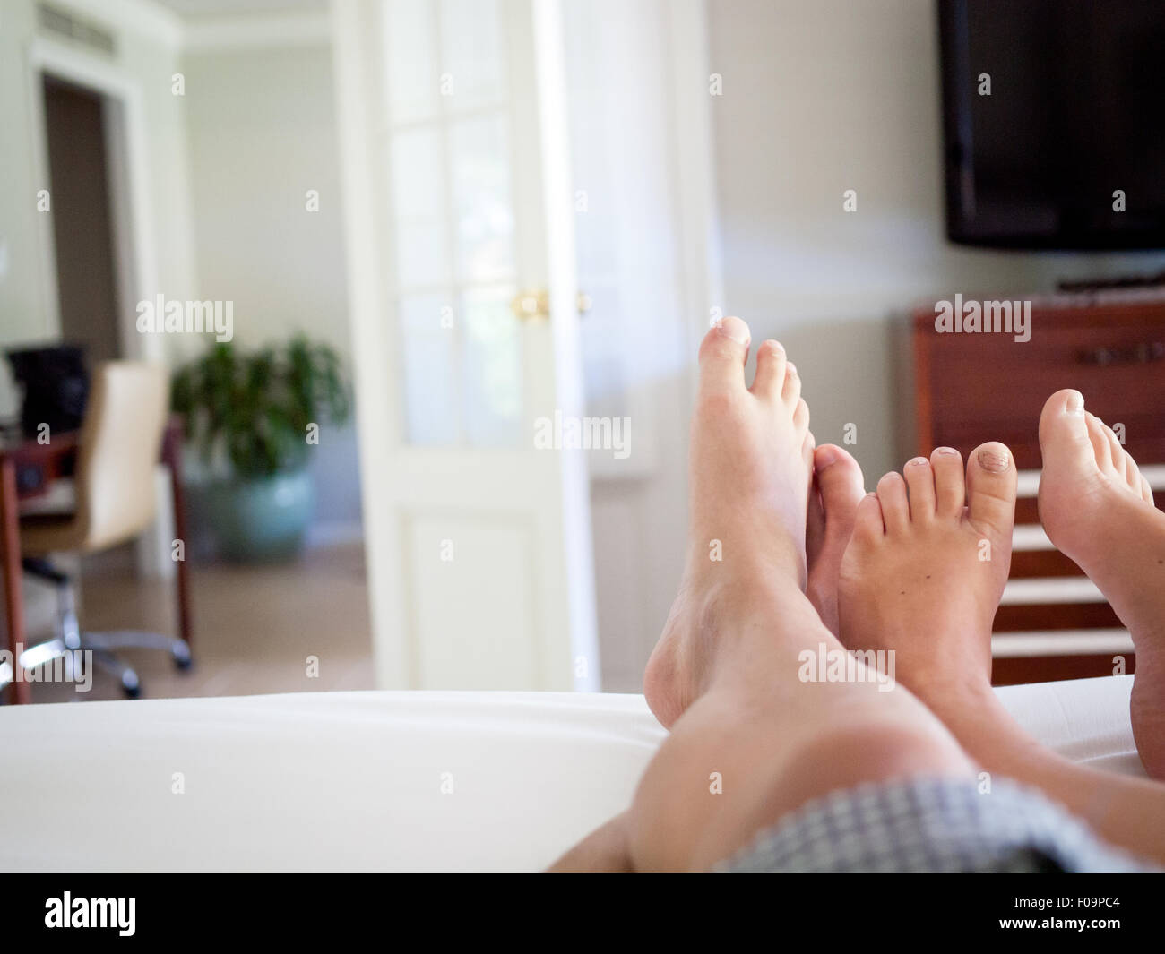 I piedi di un uomo e di una donna a letto in una stanza di un hotel suite presso il Fairmont Orchid sulla Costa Kohala, Hawai'i (Hawaii). Foto Stock