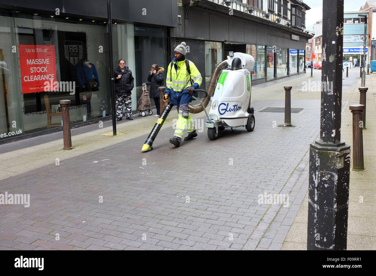 Operativa maschio utilizzando un ghiottone rifiuti elettrici street aspirapolvere a Bolton, Lancashire, Inghilterra, Regno Unito Foto Stock
