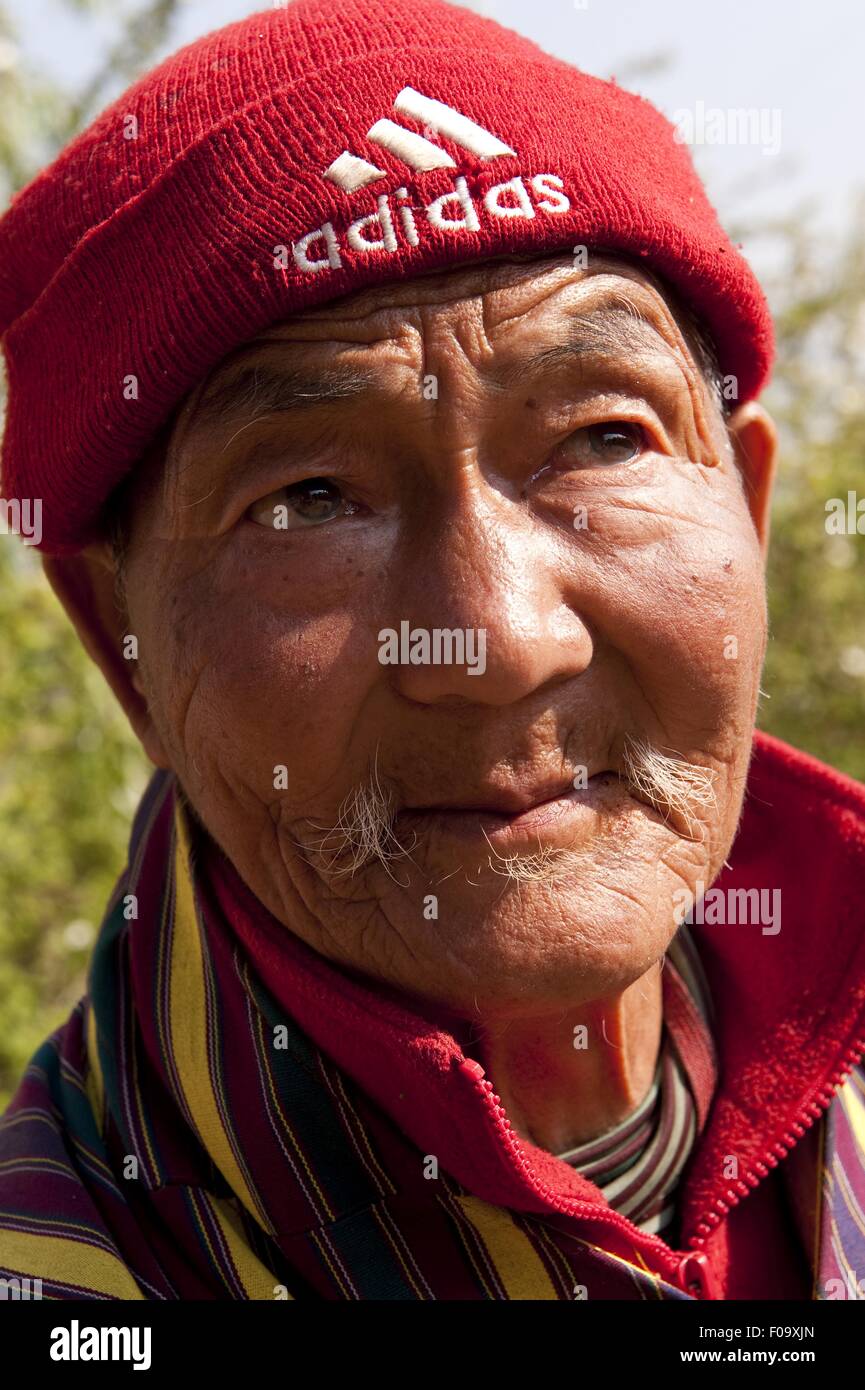 Close-up di senior uomo che indossa red cappellino guardando lontano, Paro, Bhutan Foto Stock