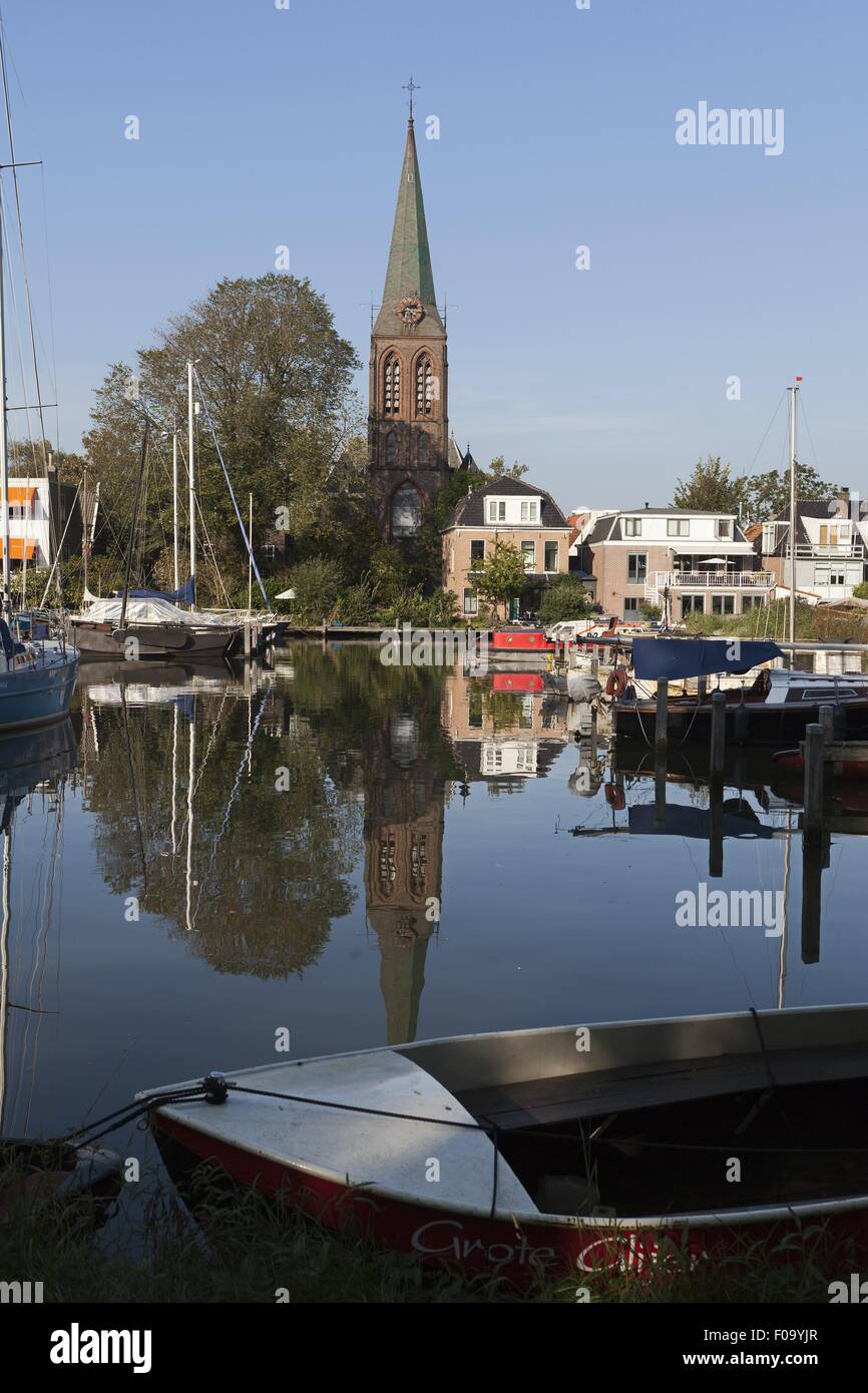 Veduta della chiesa e le barche ormeggiate nel fiume IJ, Schellingwoude, Amsterdam, Paesi Bassi Foto Stock