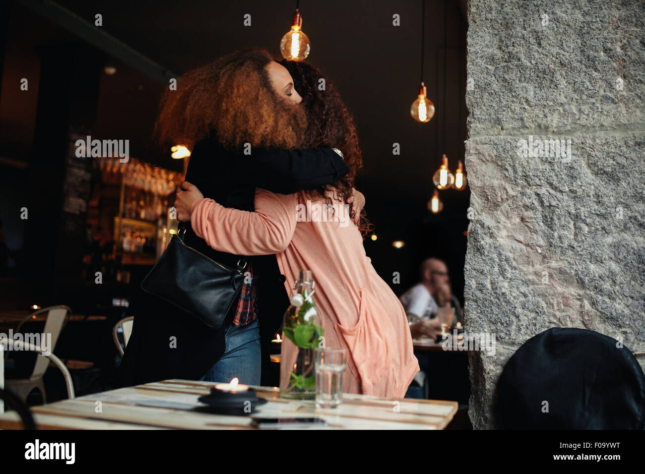 Due giovani donne riuniti in un ristorante. Gli amici che abbraccia ogni altro a un cafe'. Foto Stock