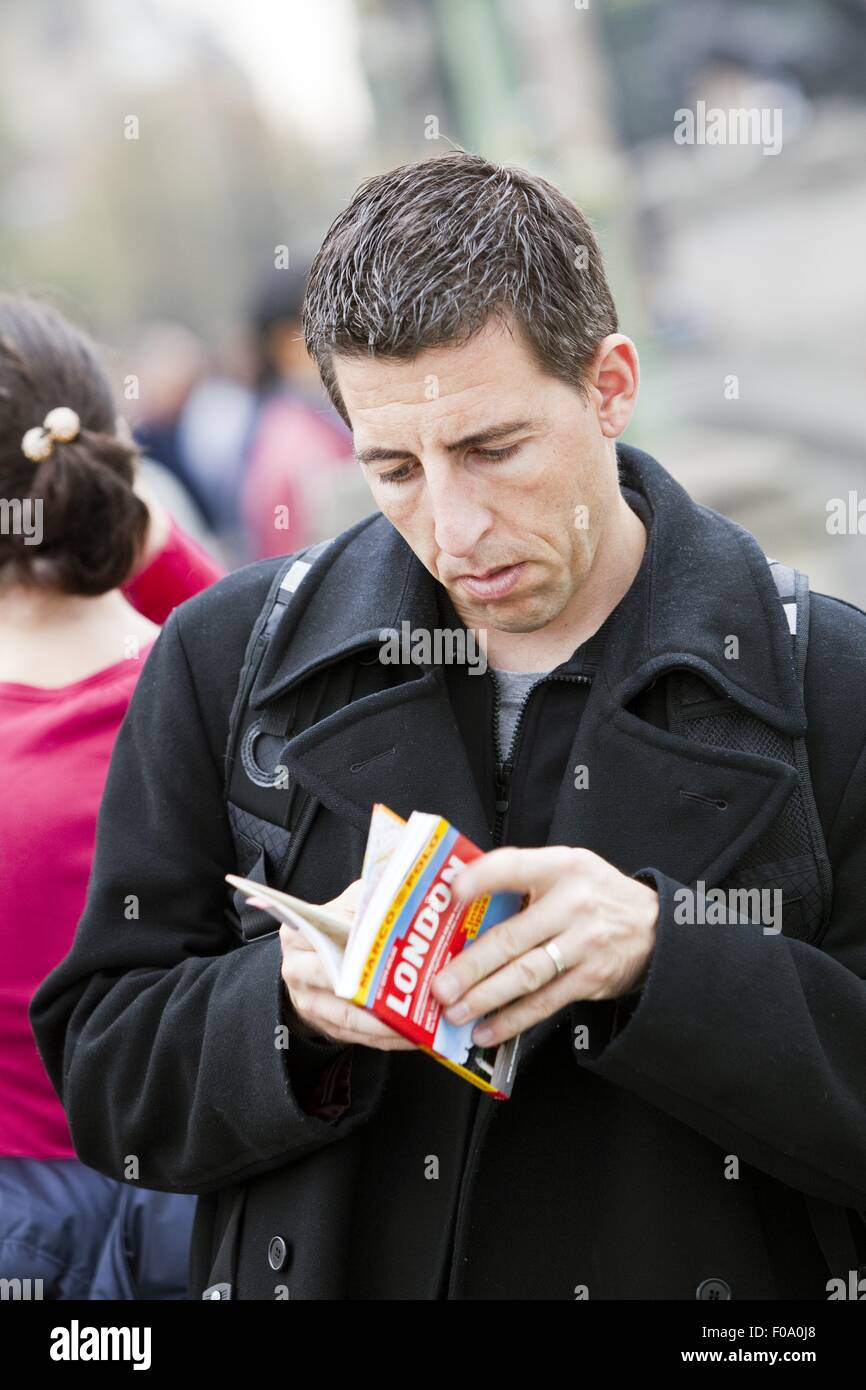 Uomo che guarda la guida turistica di Londra Foto Stock