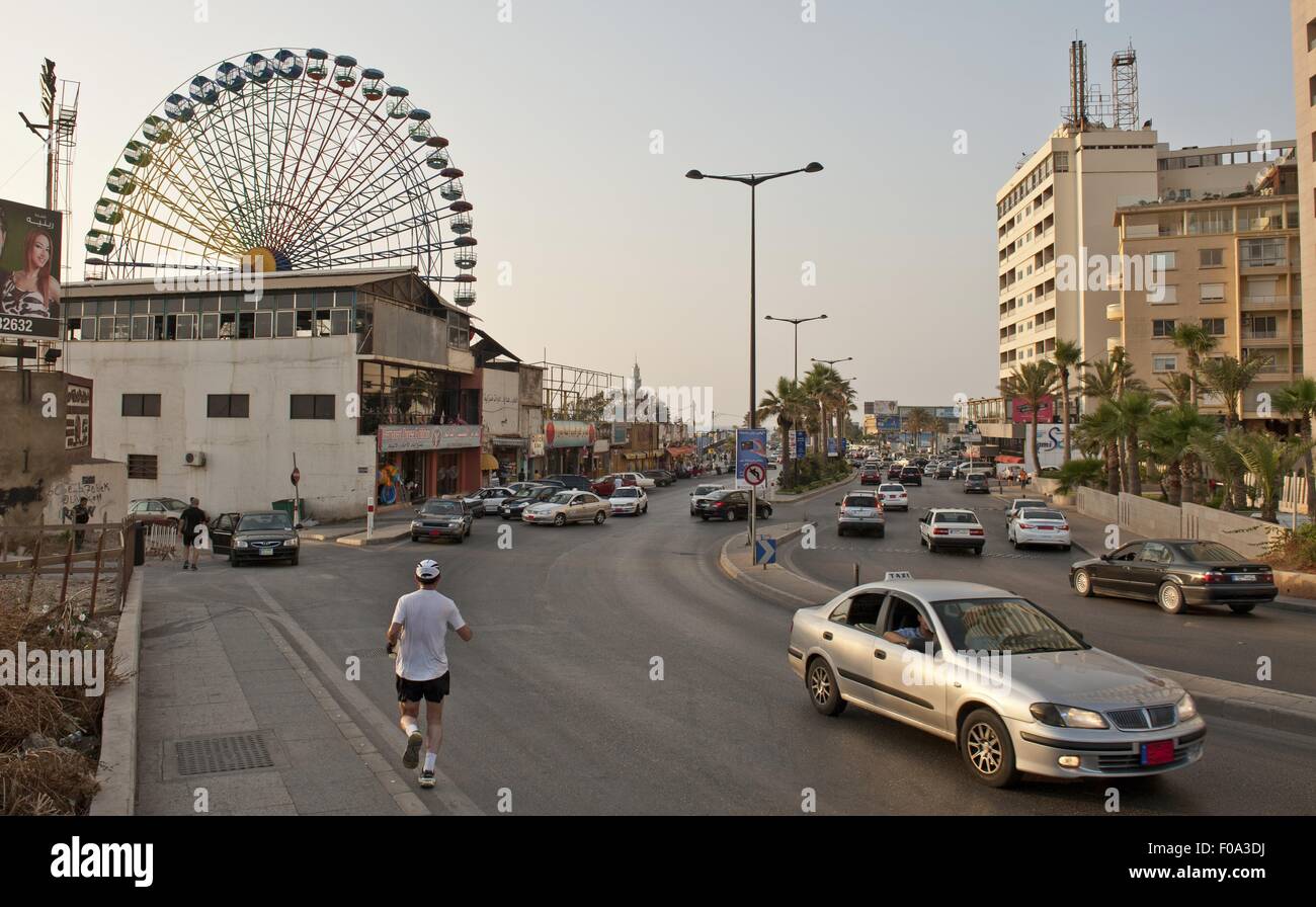 Auto e persone su strada con traghetti ruota in background al Luna park, Beirut, Libano Foto Stock