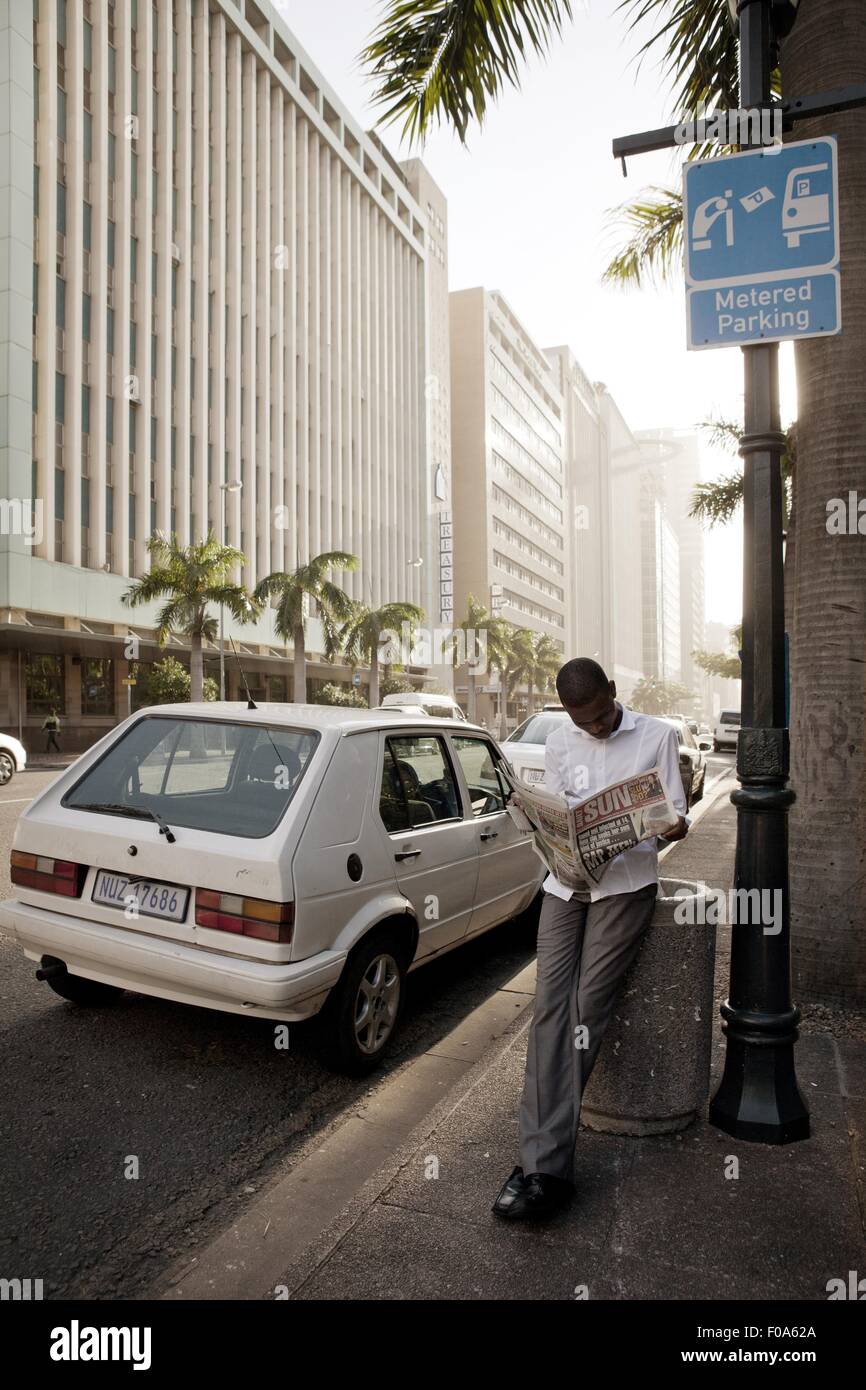 Uomo quotidiano di lettura durante la lettura sulla strada a Durban, Sud Africa Foto Stock