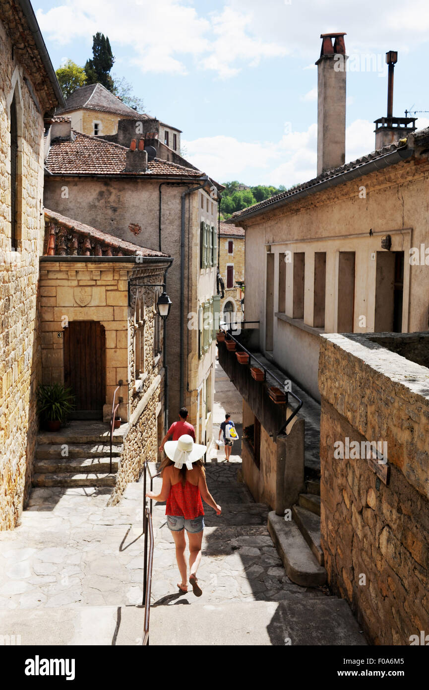 Giovane donna in vacanza che indossa una capanna Sun a piedi attraverso Puy-l'Eveque una piccola città in Francia situato nel dipartimento di Lot Foto Stock