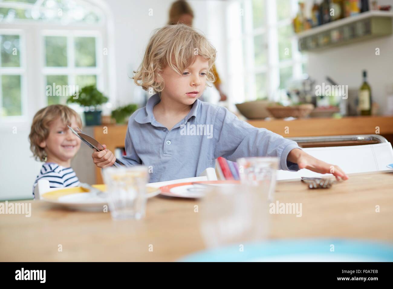 Ragazzo nella tabella di impostazione in cucina Foto Stock