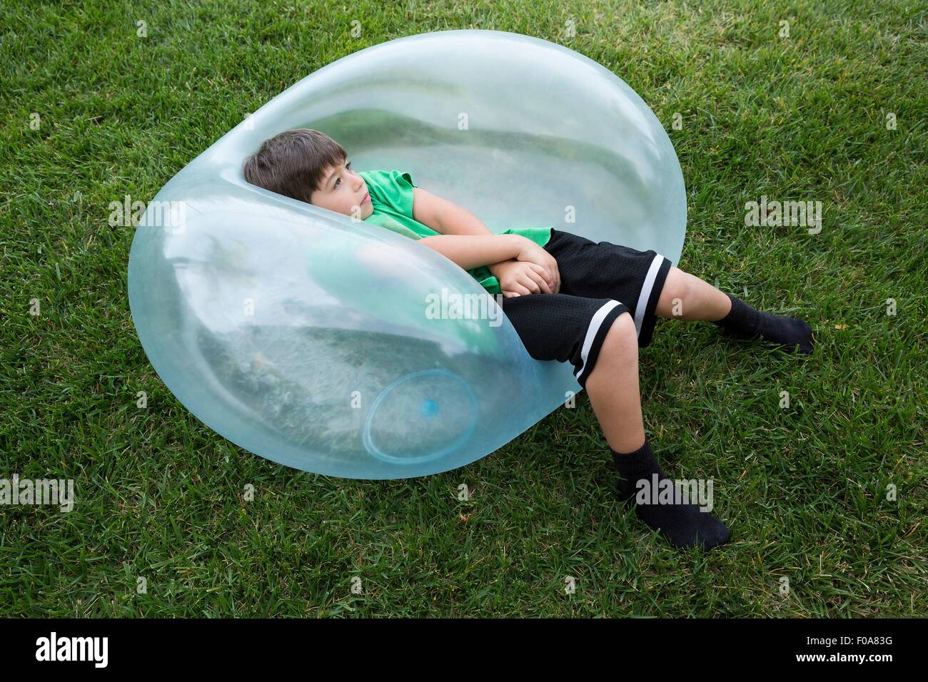 Giovane ragazzo disteso sul grande pallone gonfiabile Foto Stock