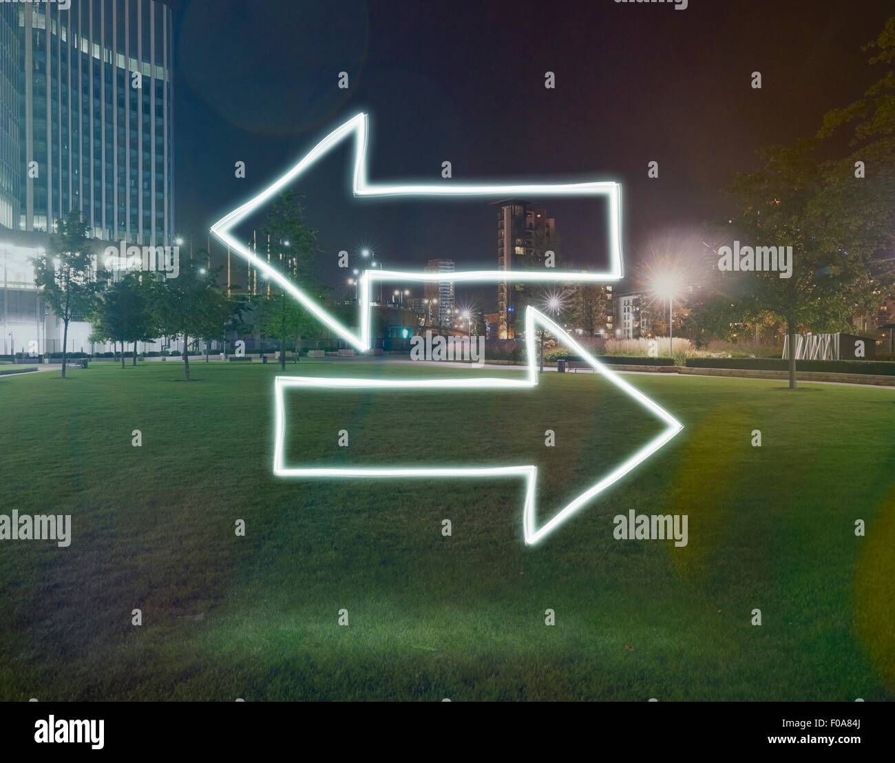 Direzione incandescente frecce verso direzioni opposte di notte, Londra, Regno Unito Foto Stock