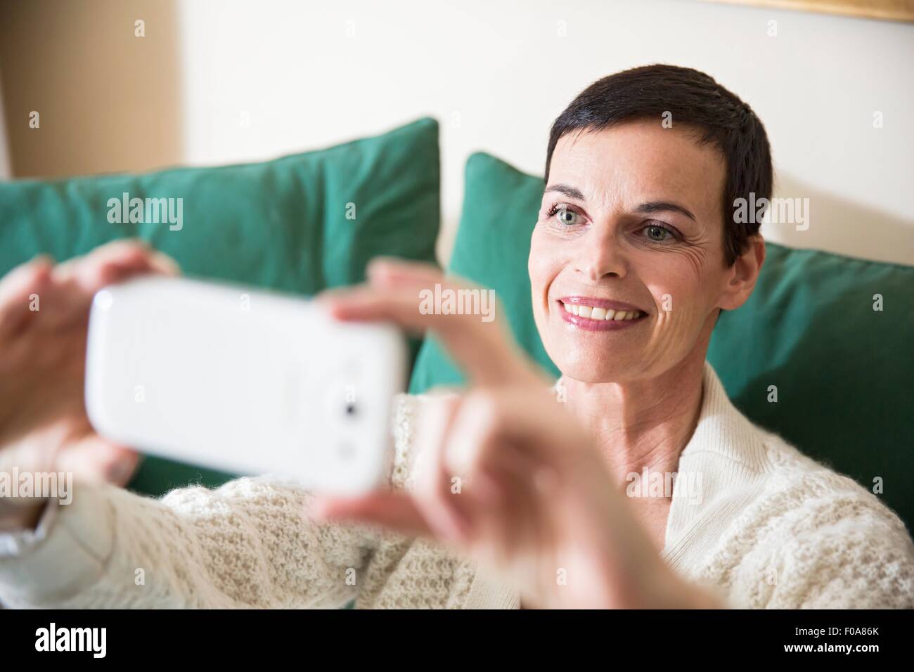 Donna prendendo selfie a casa Foto Stock