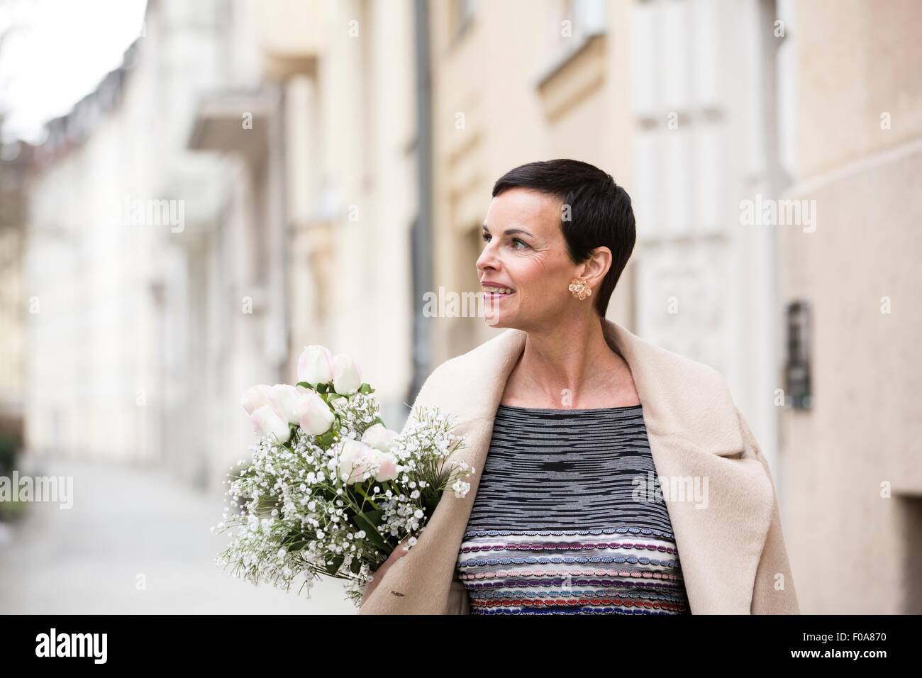 Donna con fiori camminando sulla strada Foto Stock