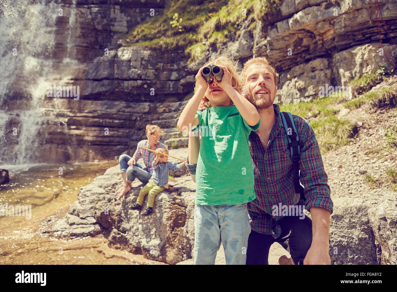Famiglia giovane esplorare accanto a cascata Foto Stock