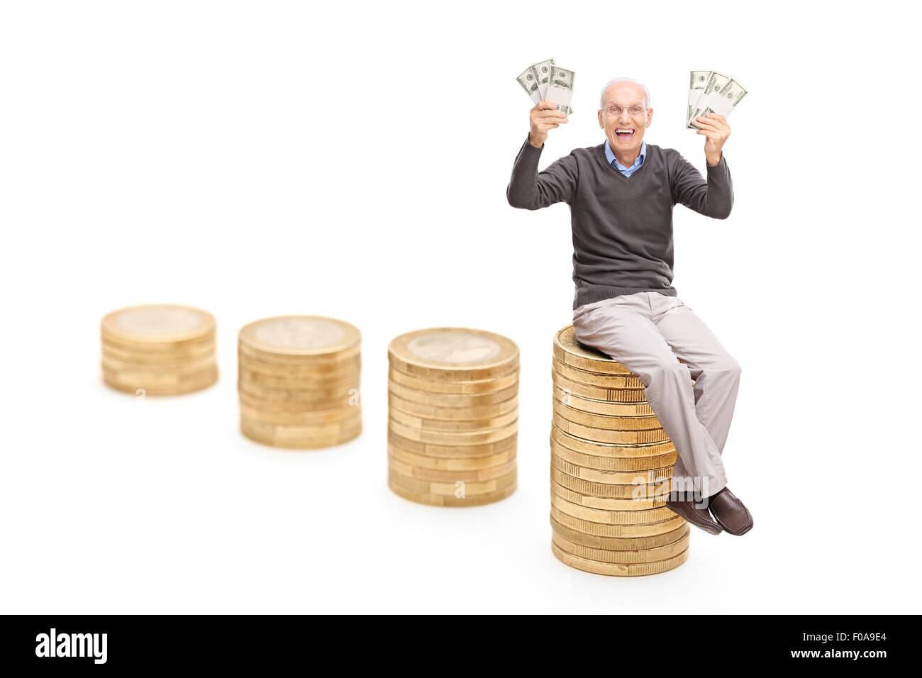 Studio shot di un contentissimo senior tenendo un sacco di soldi seduto su una pila di monete isolati su sfondo bianco Foto Stock