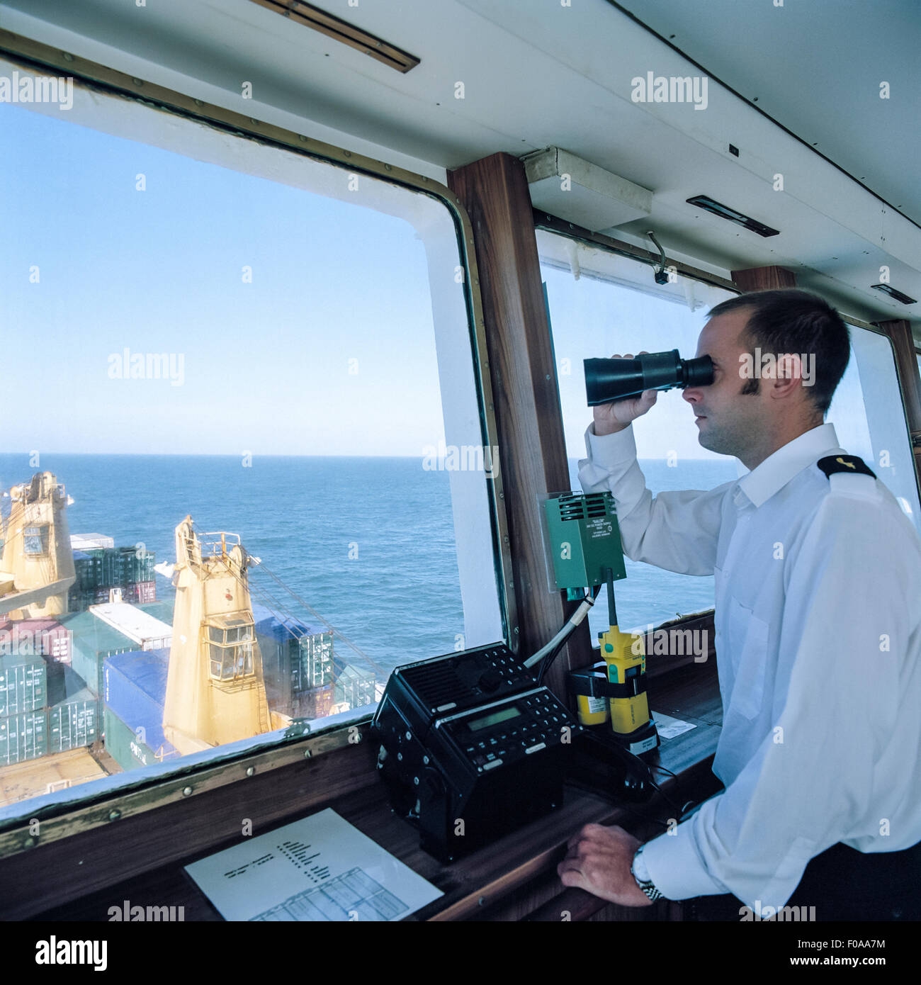 Sailor usando il binocolo sulla nave portacontainer in mare Foto Stock