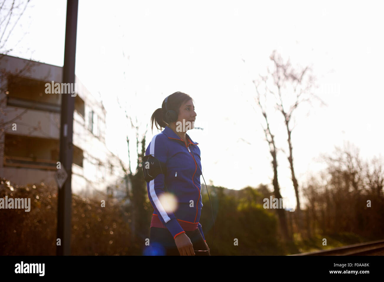 Femmina matura Runner in posizione di stazionamento per ascoltare musica sulle cuffie Foto Stock