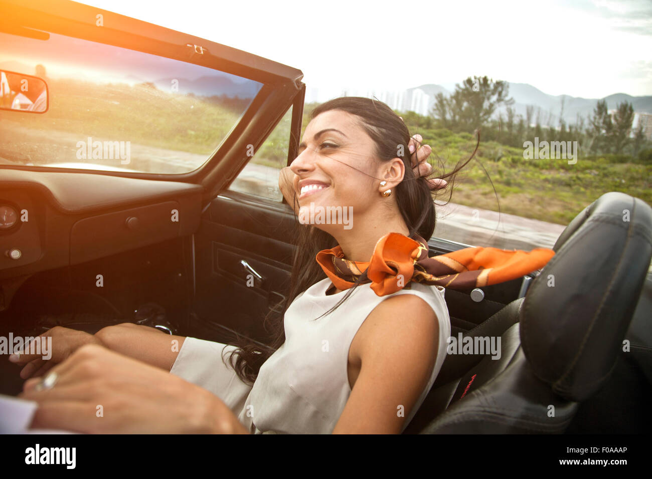 Metà donna adulta nel sedile del passeggero di autovettura convertibile Foto Stock