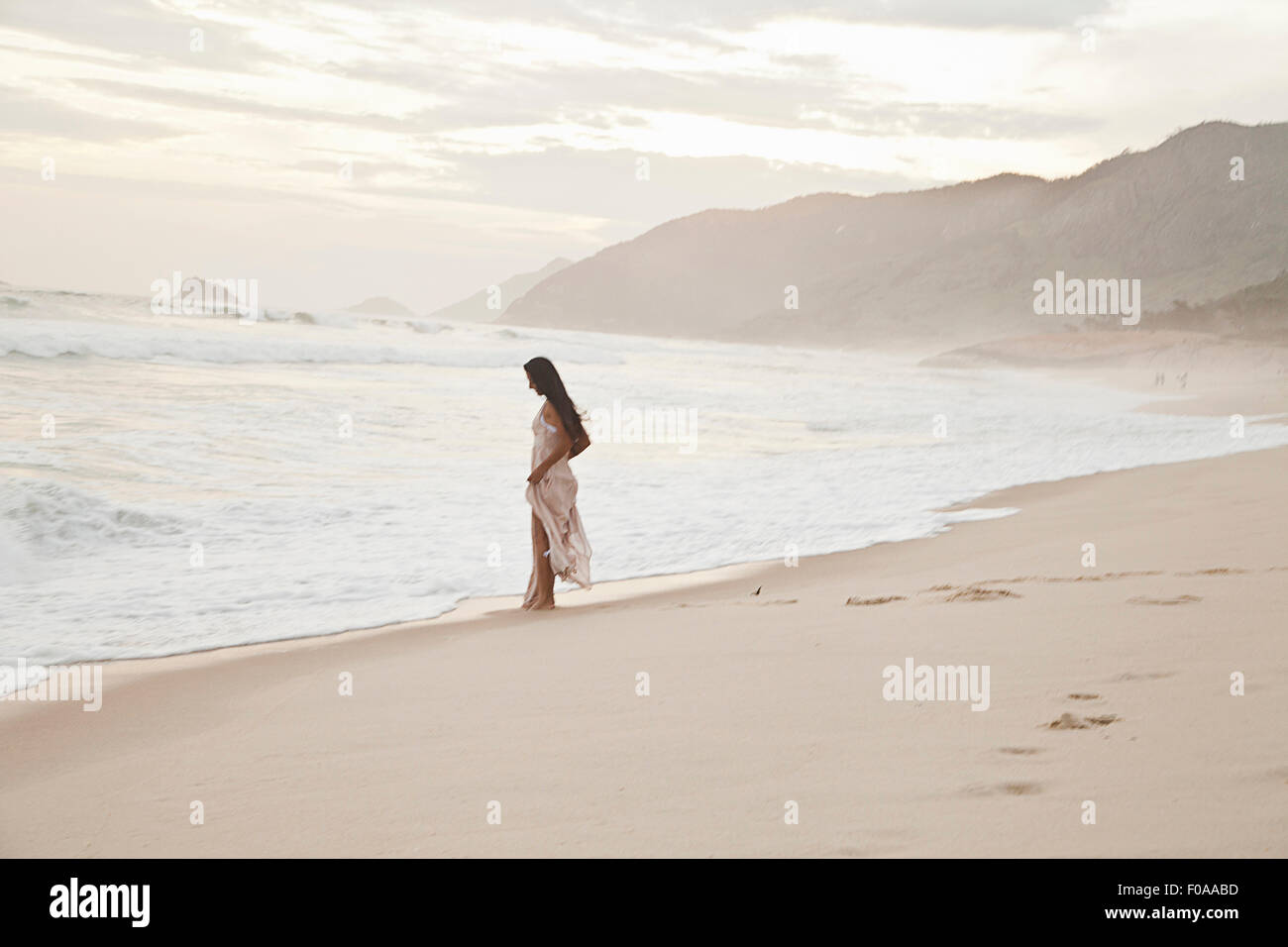 Metà donna adulta camminando lungo la spiaggia Foto Stock