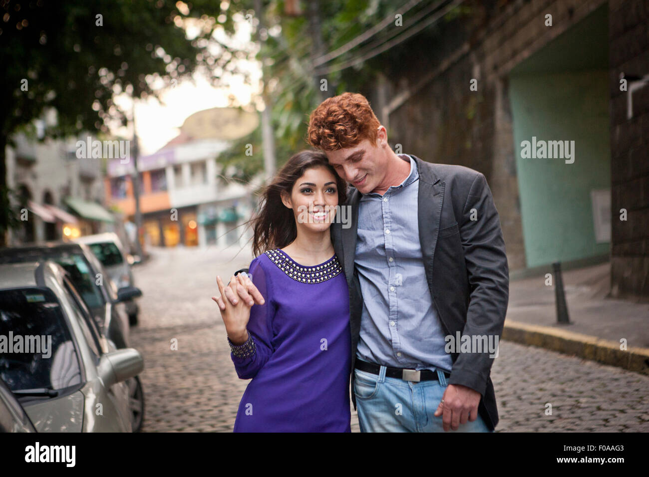 Giovane camminando lungo la strada, le braccia intorno a ciascun altro, sorridente Foto Stock