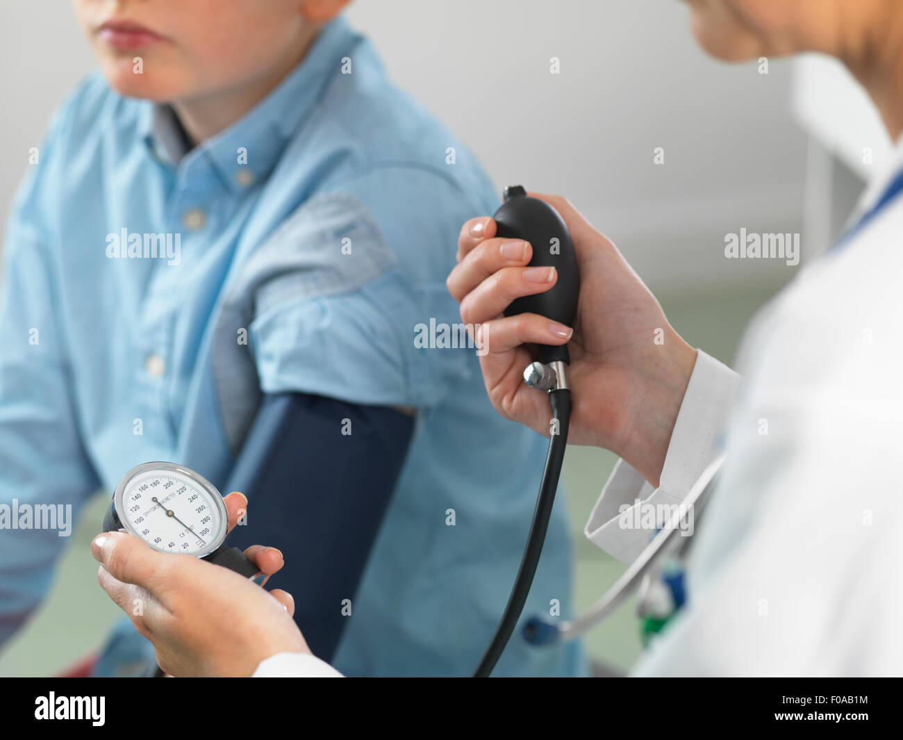 Medico di lettura della pressione sanguigna del giovane ragazzo in clinica Foto Stock