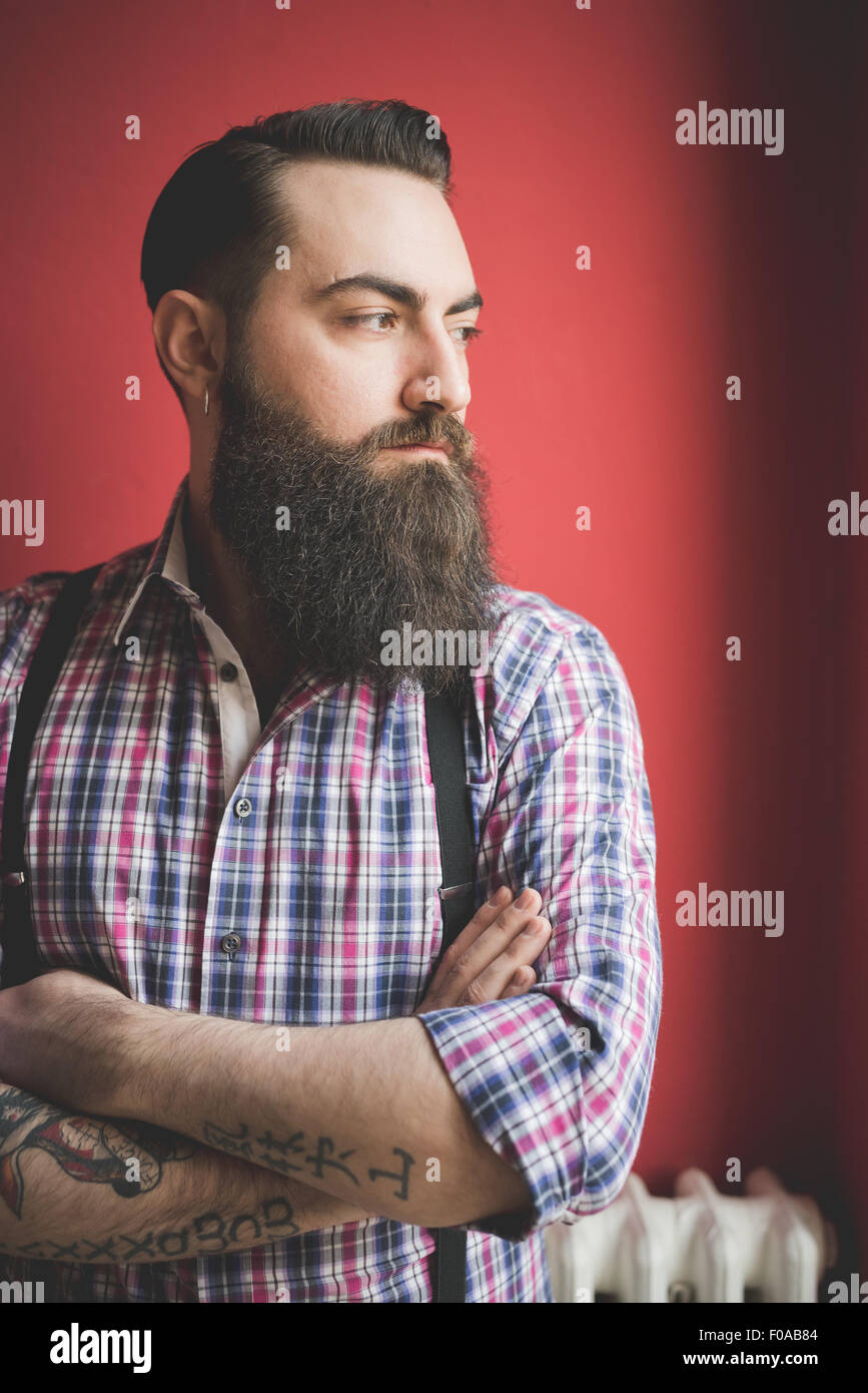 Ritratto di giovane uomo barbuto, sfondo rosso Foto Stock
