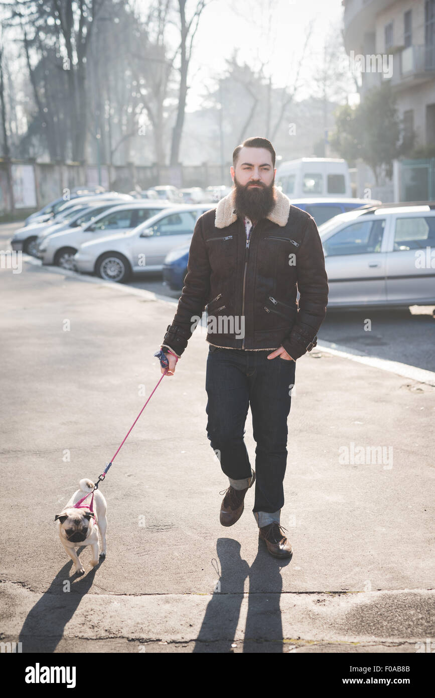 Giovane uomo barbuto cane a camminare sulla strada Foto Stock
