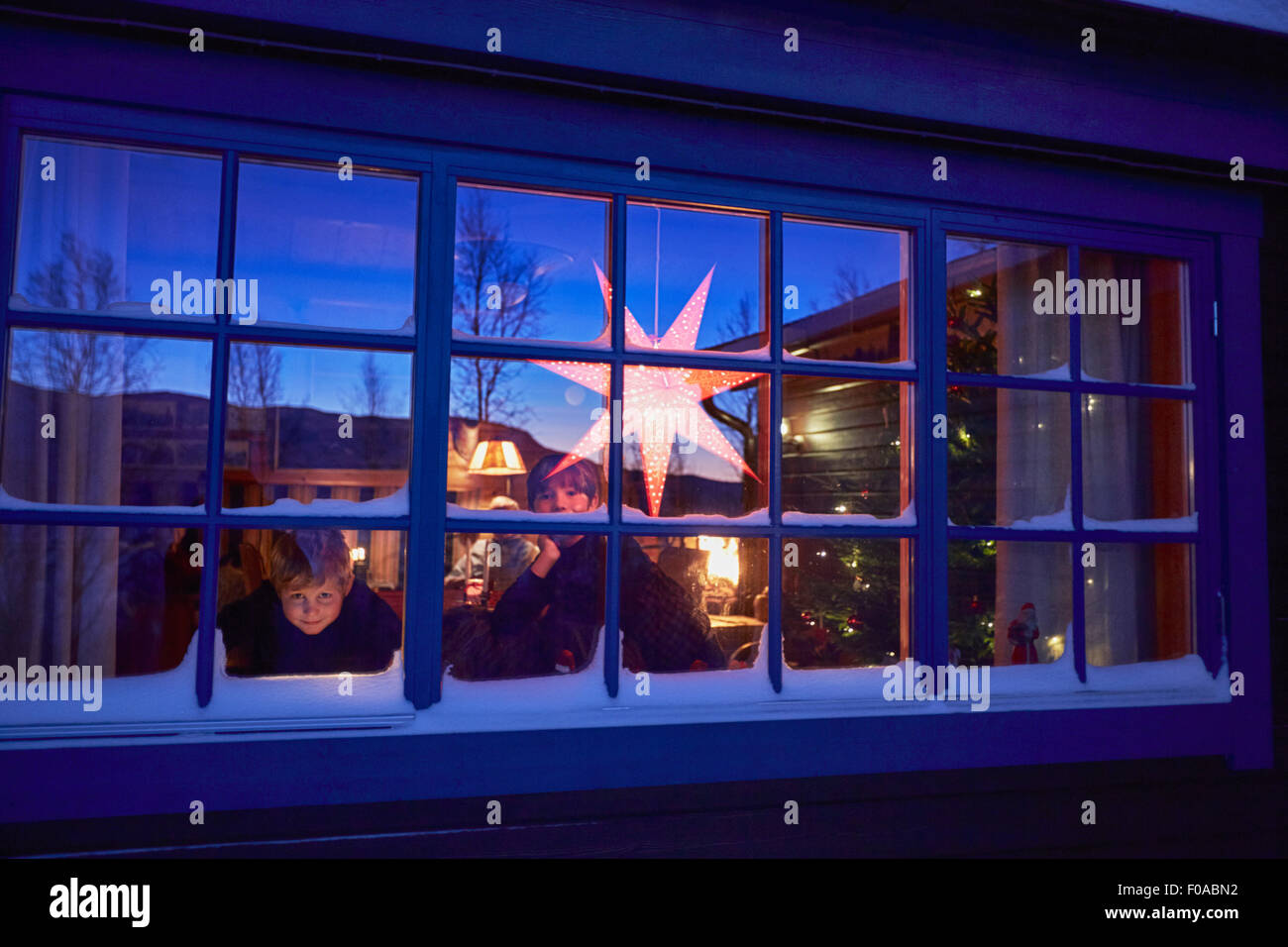 Due fratelli guardando fuori della cabina finestra di Natale di notte Foto Stock
