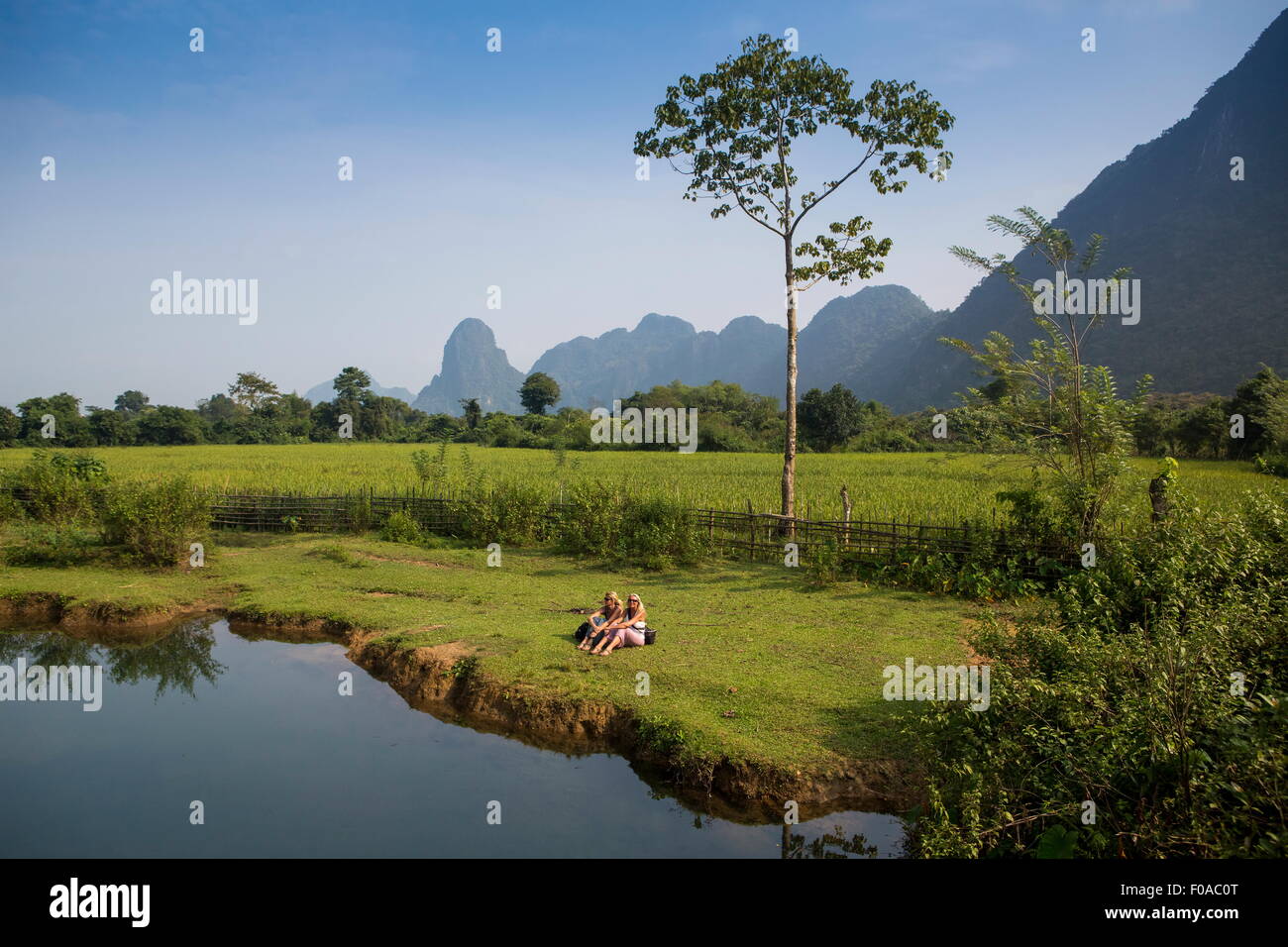 Due amiche relax su Nam Song riverbank, Vang Vieng, Laos Foto Stock