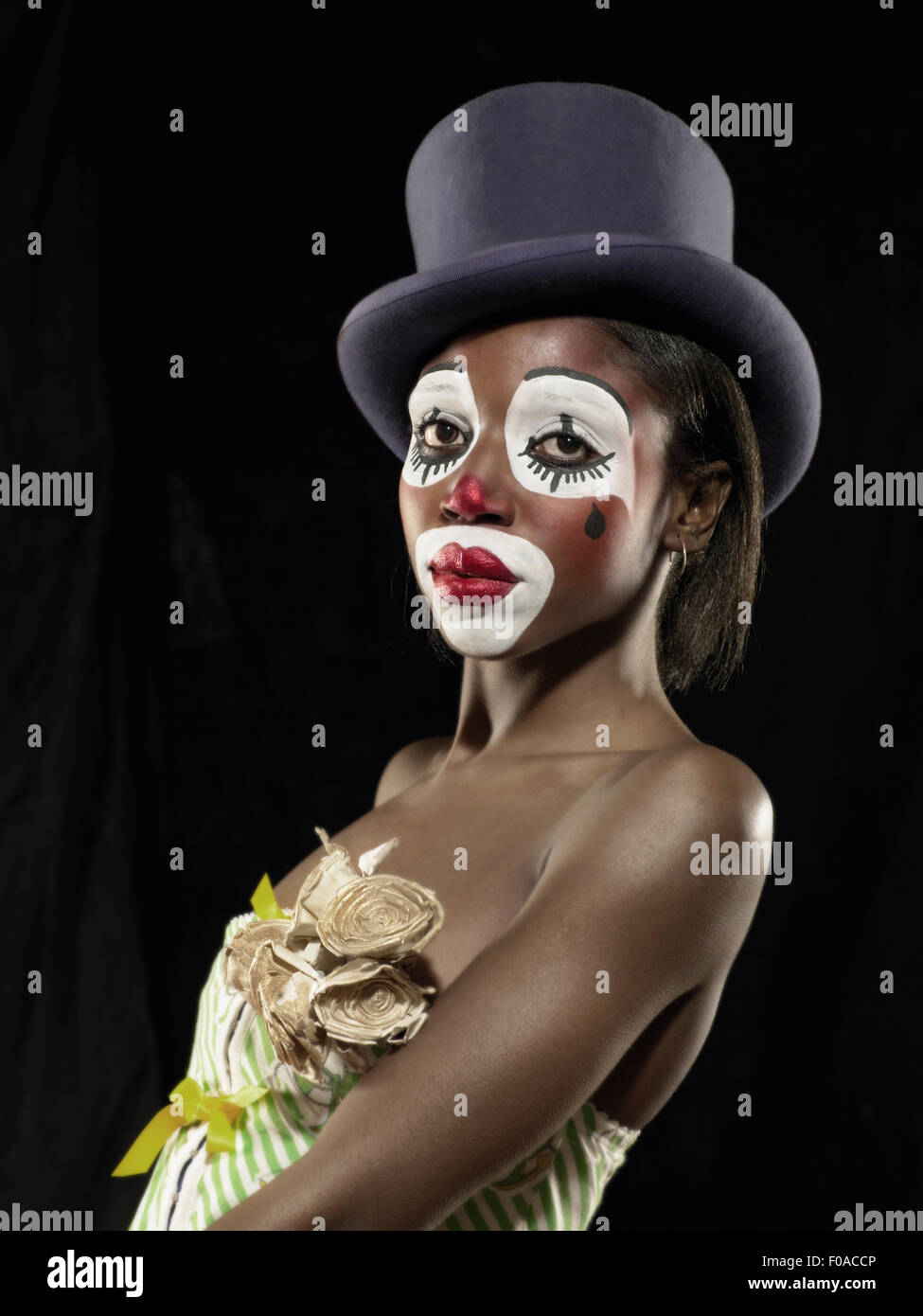 Studio Ritratto di giovane donna in faccia clown paint indossare top hat Foto Stock