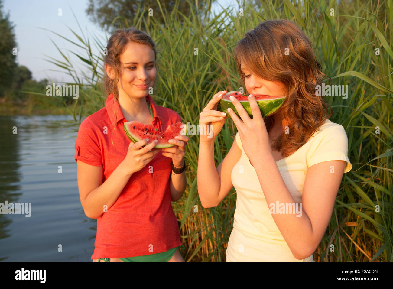 Due giovani donne mangiare anguria fette a Lakeside Foto Stock