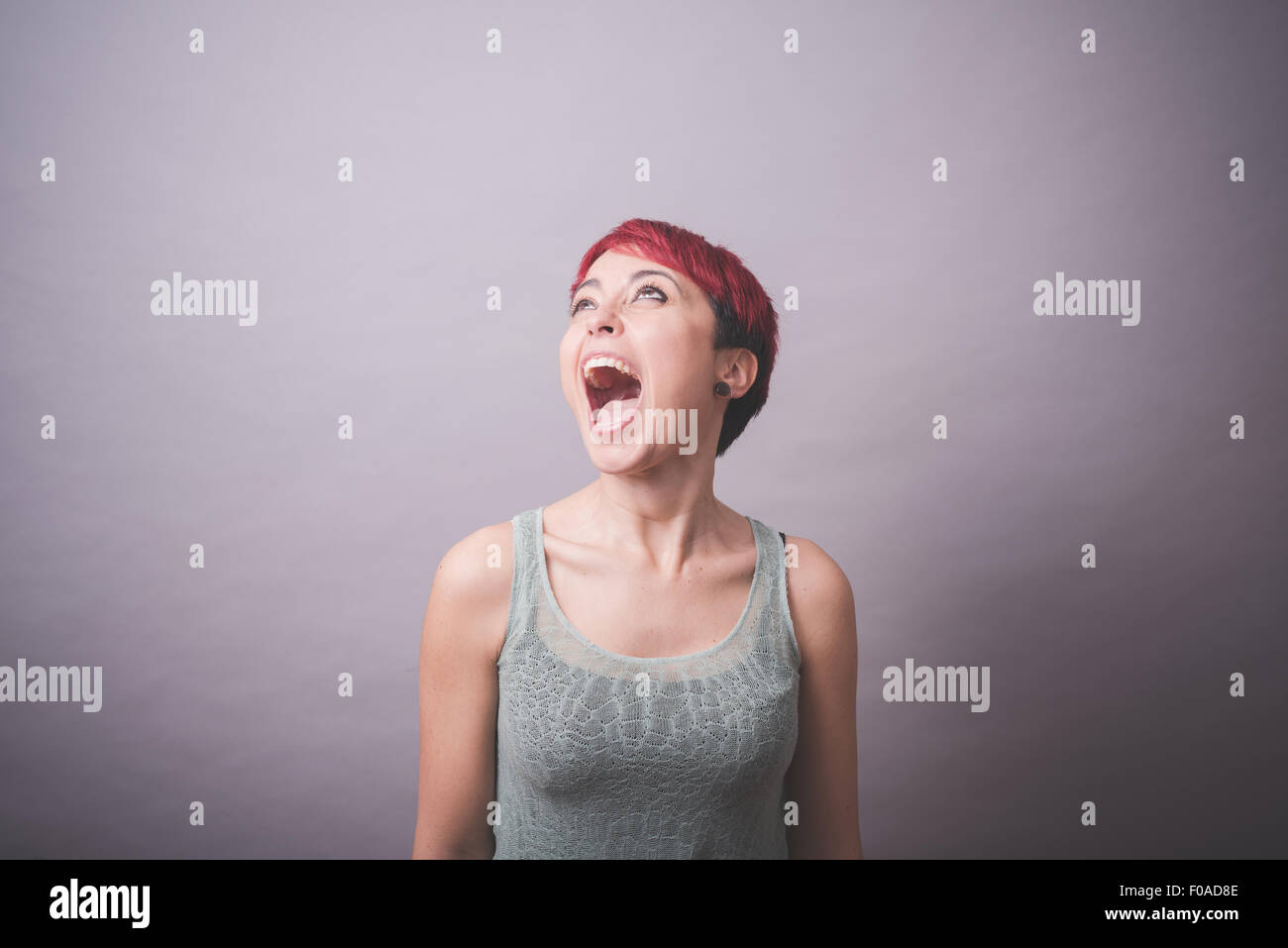 Studio Ritratto di giovane donna con corti capelli rosa urlando Foto Stock