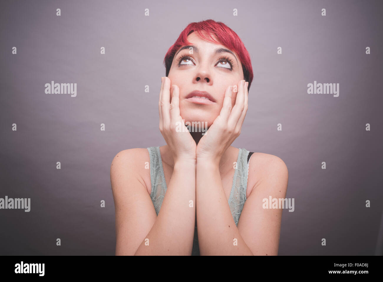 Studio Ritratto di giovane donna con corti capelli rosa con le mani sulle guance Foto Stock