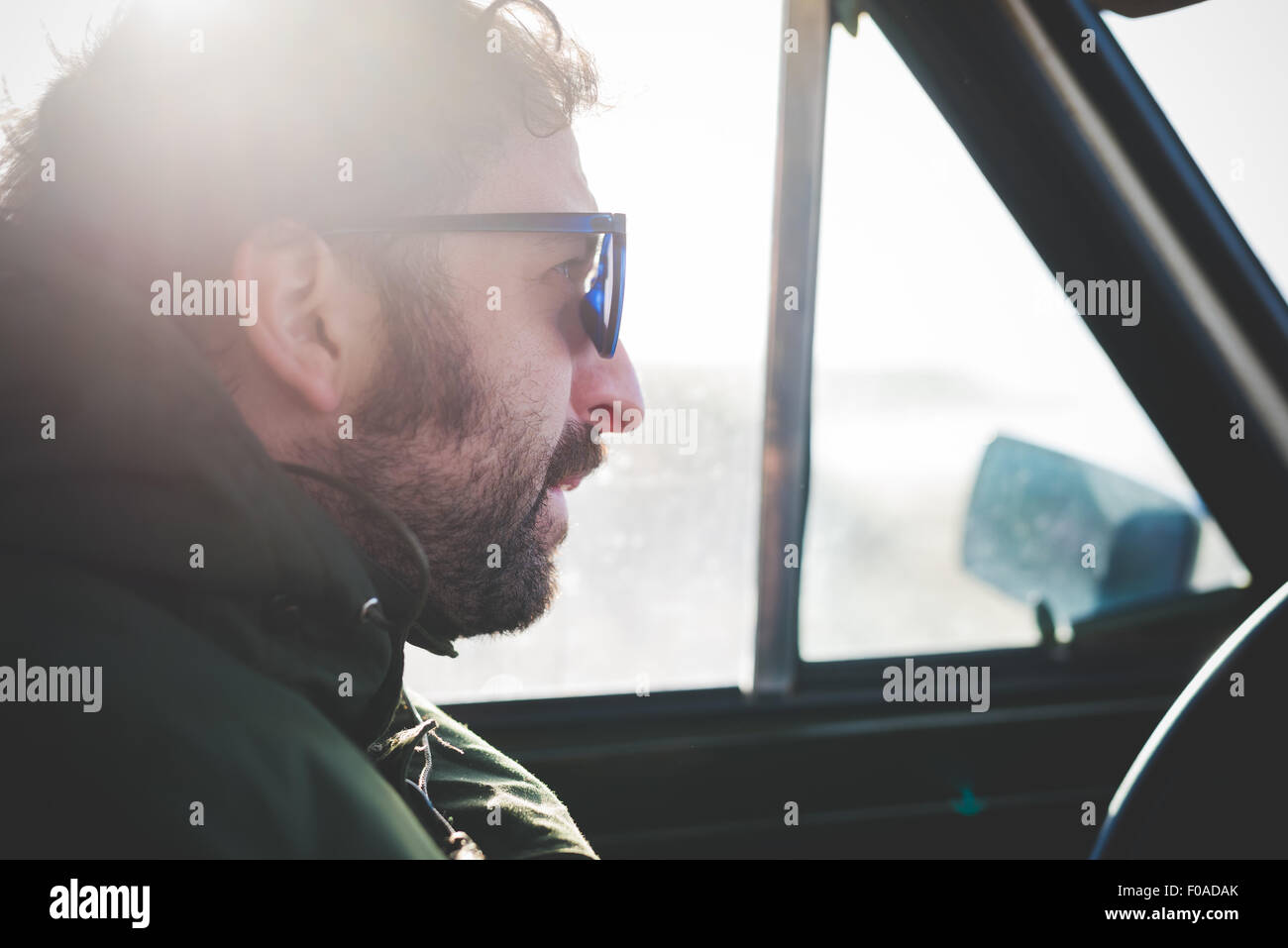 In prossimità di metà uomo adulto indossando occhiali da sole in auto soleggiato Foto Stock