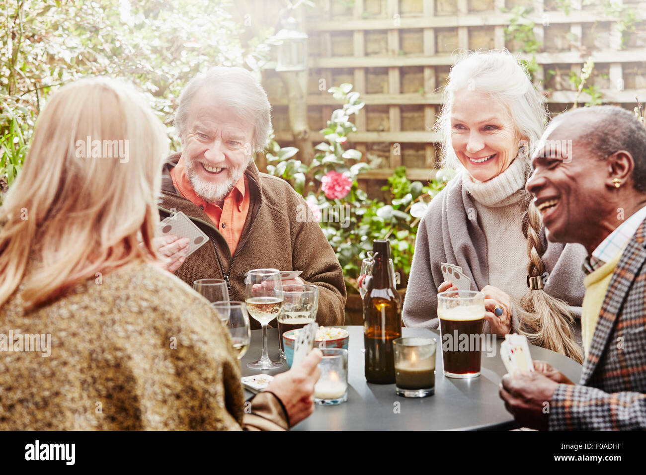 Senior gli amici a bere e giocare a carte in giardino Foto Stock