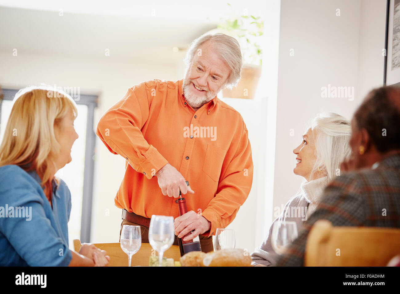 Senior uomo apertura del vino con gli amici Foto Stock